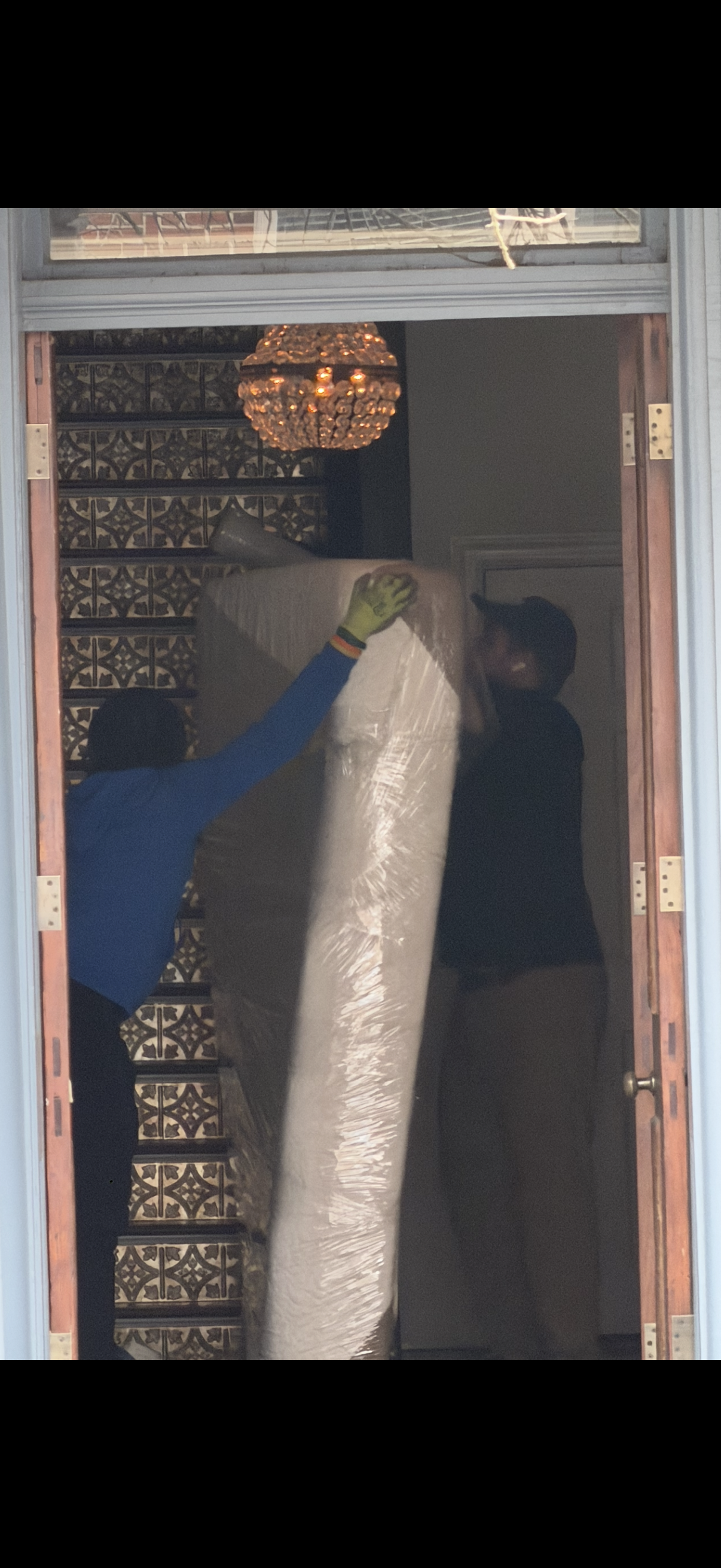 RVA Movers crew carrying a wrapped mattress through an ornate doorway